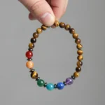 Bracelet 7 chakras oeil de tigre tenu en main, les sept perles visibles