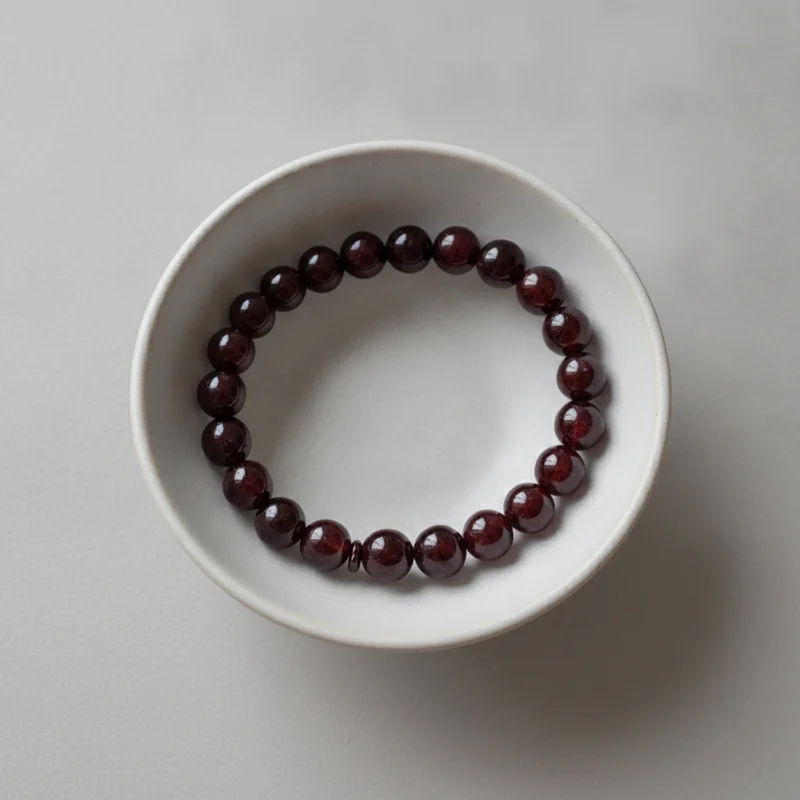 Bracelet grenat dans une coupelle claire