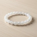 Bracelet jade blanc de trois quarts sur bois clair