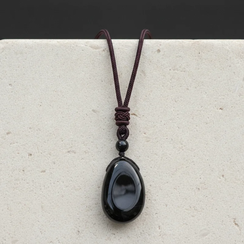 Pendentif obsidienne posé sur pierre claire