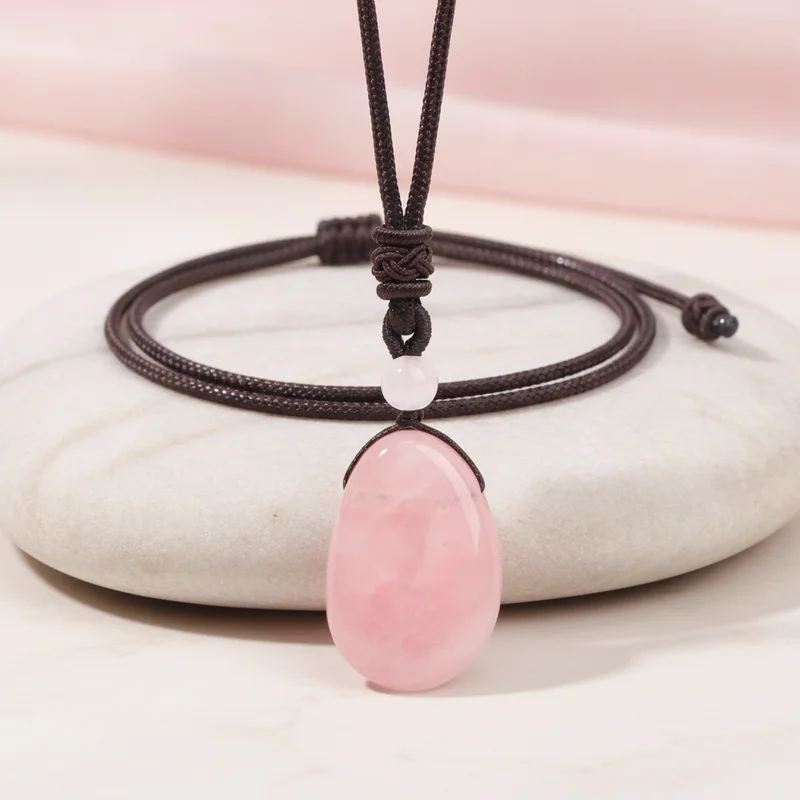 Pendentif quartz rose posé sur pierre claire